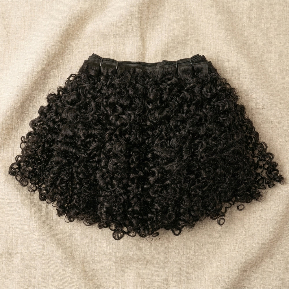 Adéorí Burmese Curly virgin hair extension bundle flat lay on earthy surface